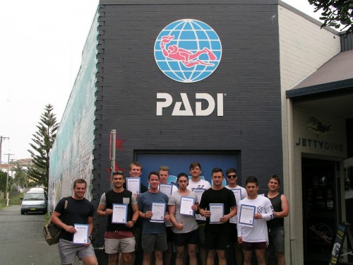 Group of divers holding certification certificates outside of Jetty Dive Centre