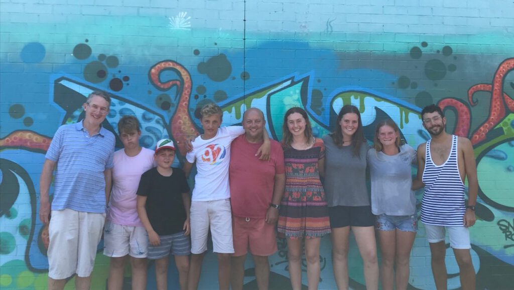 PADI Open Water Scuba Diver students with certificates against graffiti wall