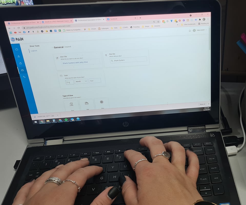 PADI Electronic Logbook being filled in on a black laptop, hands typing on keyboard.